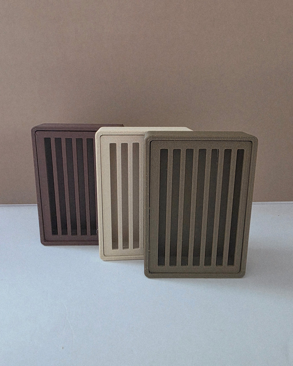 Eco-friendly Wood PLA soap savers standing in three neutral tones: brown, beige, and taupe.