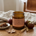 Hand-poured Autumn and Apple Orchard scented candle in an amber glass jar featuring crisp fall apples and autumn leaves.