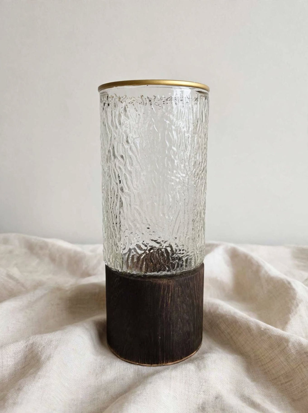 Clear textured glass vase with bark texture and gold rim on a wooden base