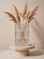 Clear square glass vase with geometric ice-crackle texture displayed on a travertine pedestal