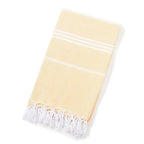 Folded pale yellow Turkish beach towel with white stripes and tassels on white background
