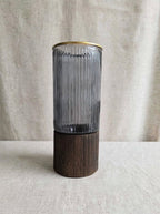 Smoky ribbed glass vase with gold rim on a wooden base, studio shot
