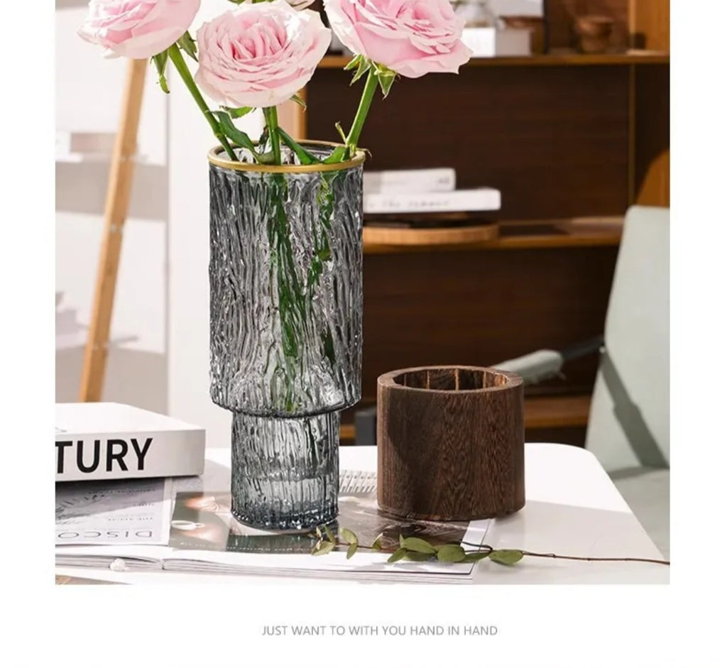 Textured glass vase with gold rim styled with pink roses beside its wooden base