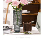 Textured glass vase with gold rim styled with pink roses beside its wooden base