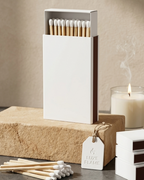 Minimalist white matchbox with wooden safety matches next to a candle