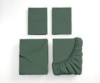 A set of folded bedding pieces in a muted sage green color, including two folded flat sheets or pillowcases, a folded fitted sheet with a ruffled edge, and a folded pillowcase, arranged on a clean white background.