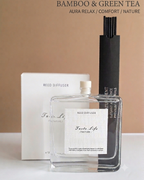 A clear glass reed diffuser bottle labeled 'Fae for Life / Nature' stands in front of a white box and a tall black reed holder, with text at the top reading 'BAMBOO & GREEN TEA' and 'AURA RELAX / COMFORT / NATURE'.