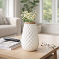 White woven-patterned vase with flowers on a coffee table in a living room.