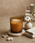 SOMA HOME Fresh Cotton Scented Candle in an amber textured glass jar, styled on a stone coaster with cotton bolls, folded linen, and a ceramic mug.